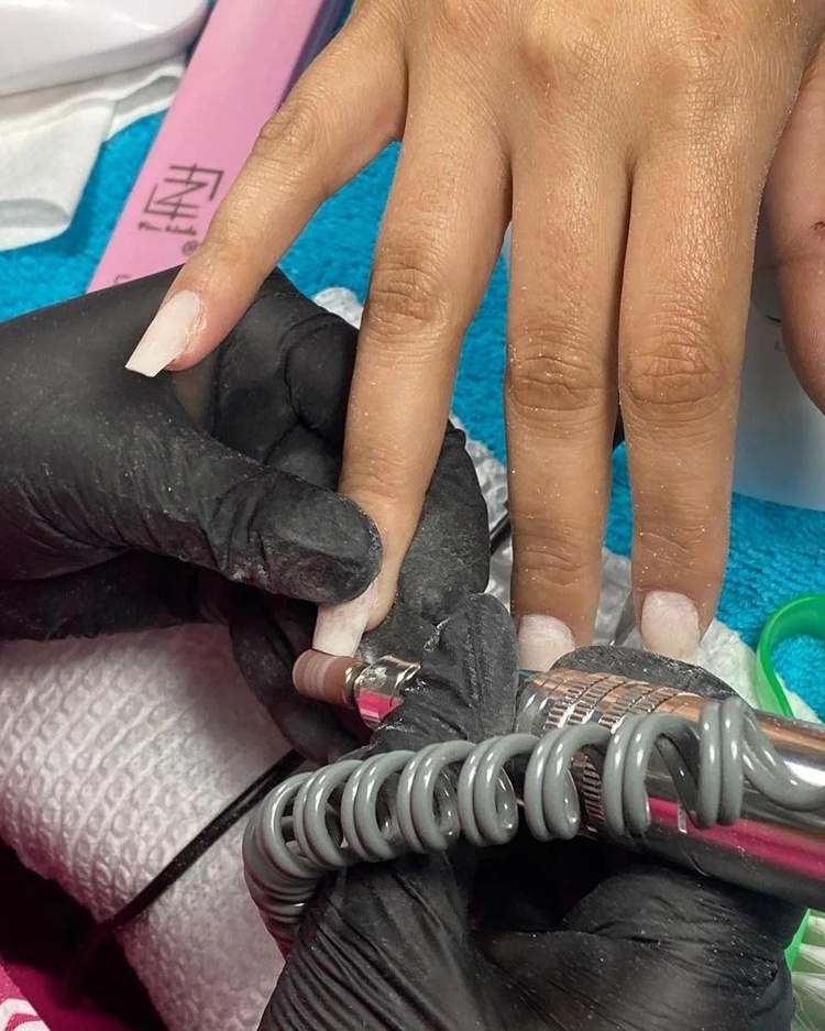 Close-up of beautiful long white square acrylic nails being manicured, showcasing fine detailing.