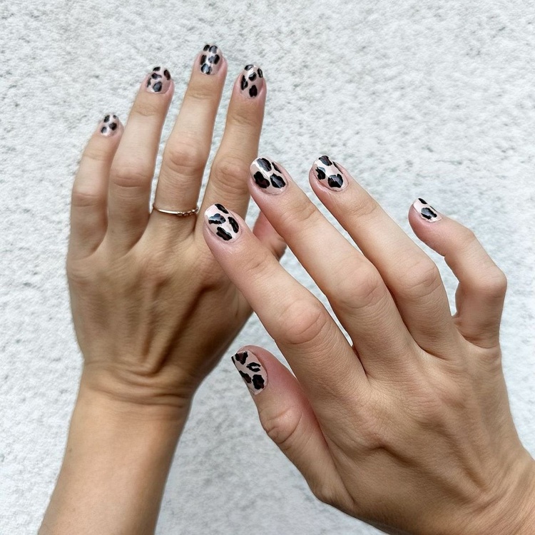 Two hands with animal print nails including black, brown, and cream hues, showcasing a unique design.