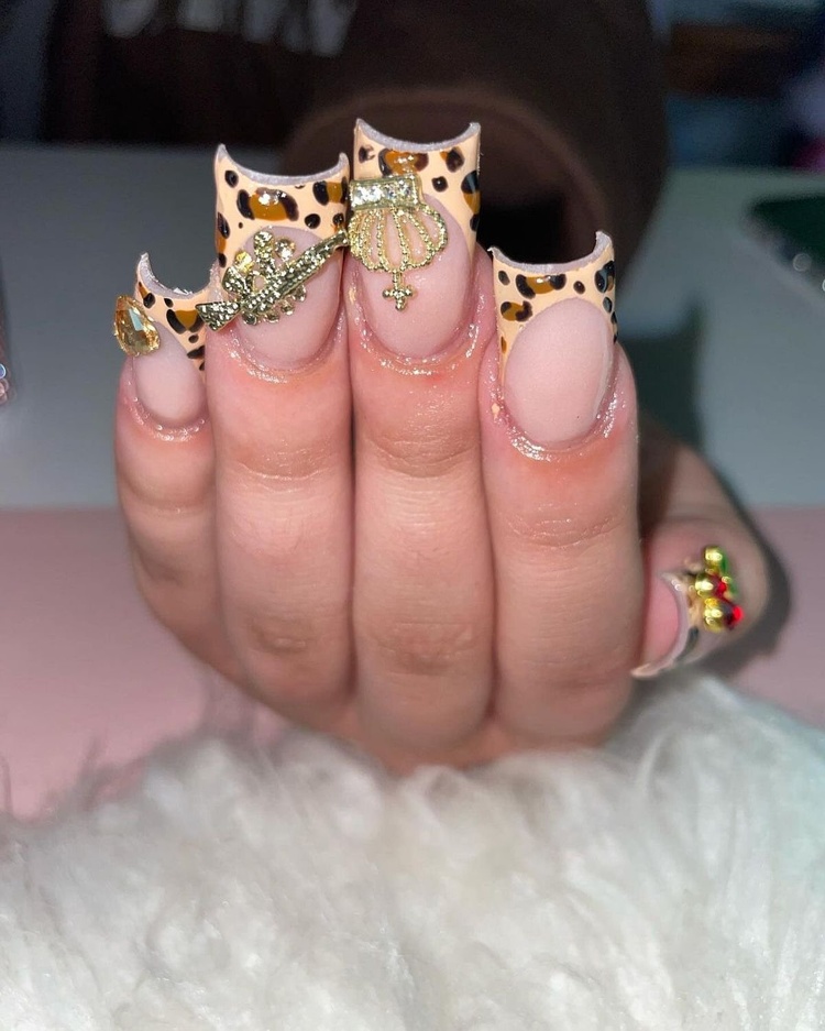 Close-up of animal print nails featuring gold accents, showcasing a stylish manicure.