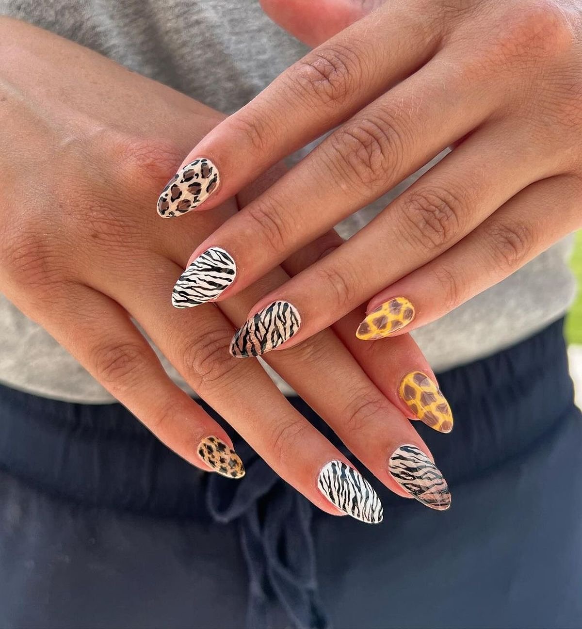 A beautiful set of animal print nails showcasing vibrant patterns in yellow, brown, black, and white.