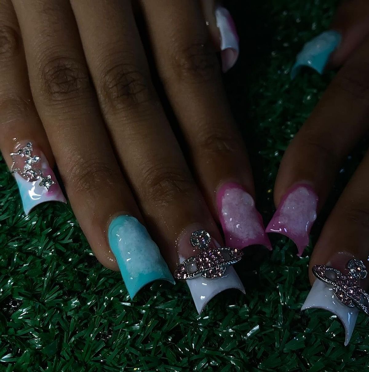 Close-up of beautifully designed aqua, pink, and white glitter nails on a sparkling background.