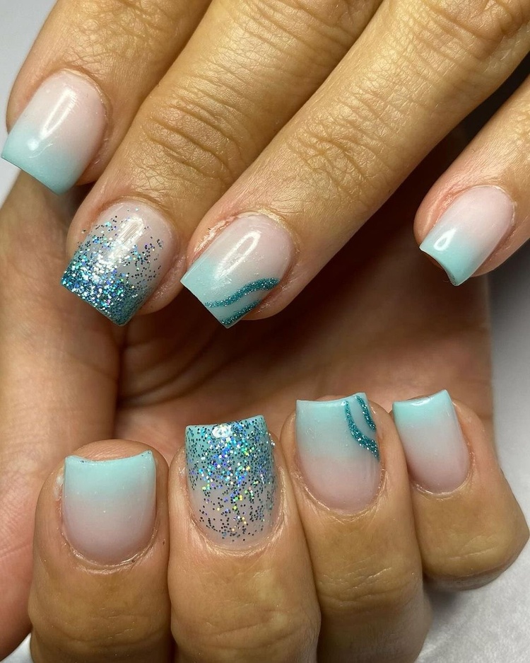 Beautiful acrylic nails featuring aqua color, glitter accents, and a shiny finish.