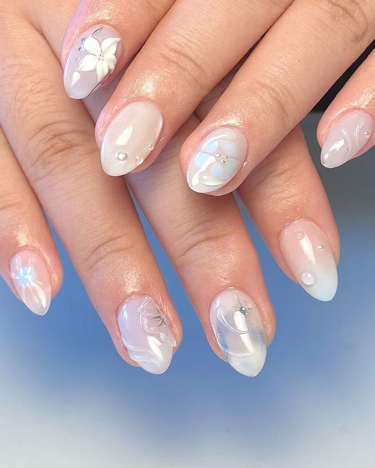 Gorgeous baby blue and white nails adorned with floral designs, highlighting a delicate and stylish aesthetic.