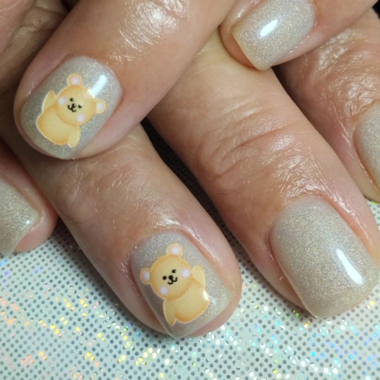 Beige glitter nails adorned with cute bear designs, showcasing a fun and playful style.