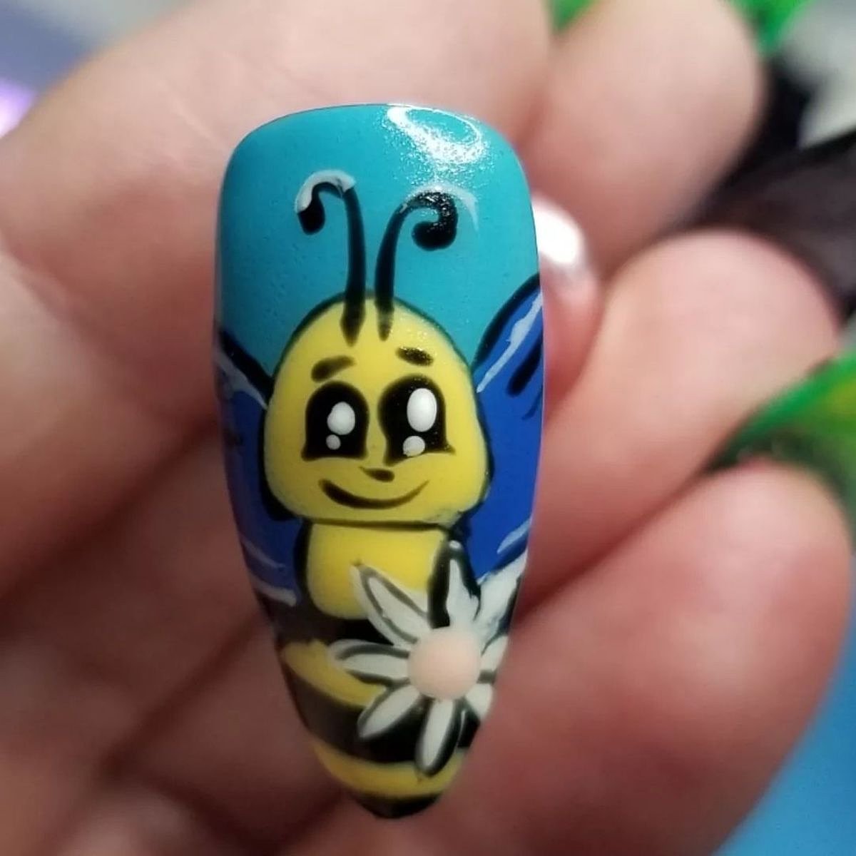 A cute bee nail art design featuring yellow and blue colors.