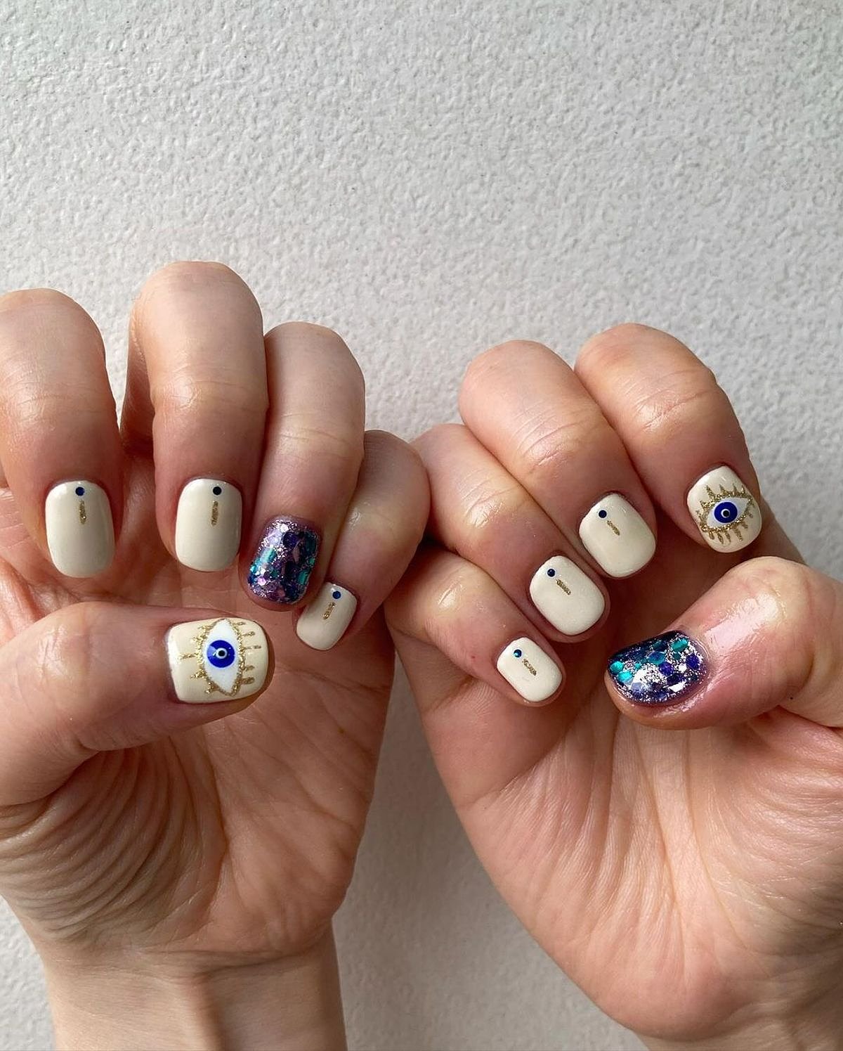 This image showcases beautifully manicured beige nails featuring unique eye art and glitter accents.