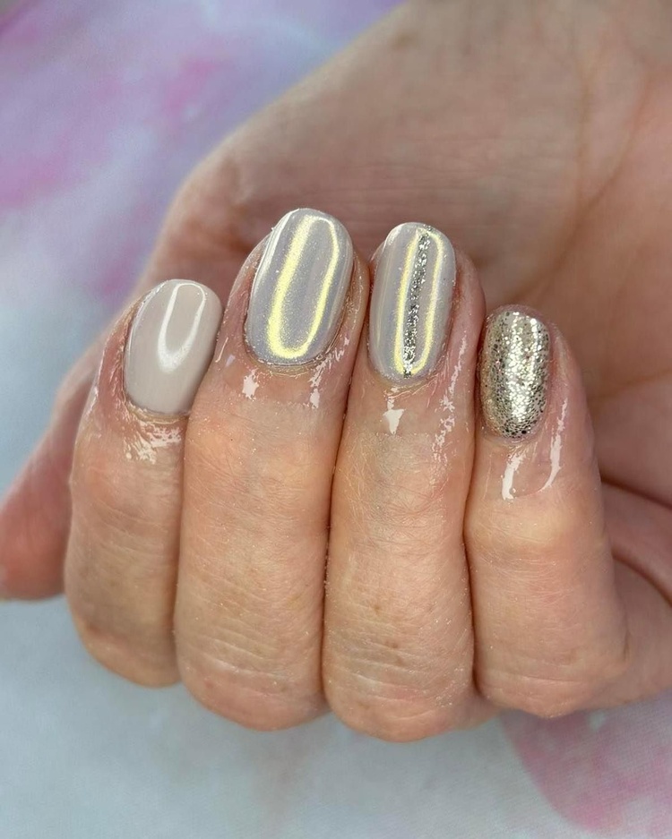 Close-up of elegant beige and gold glitter nails against a soft background, showcasing a refined manicure.