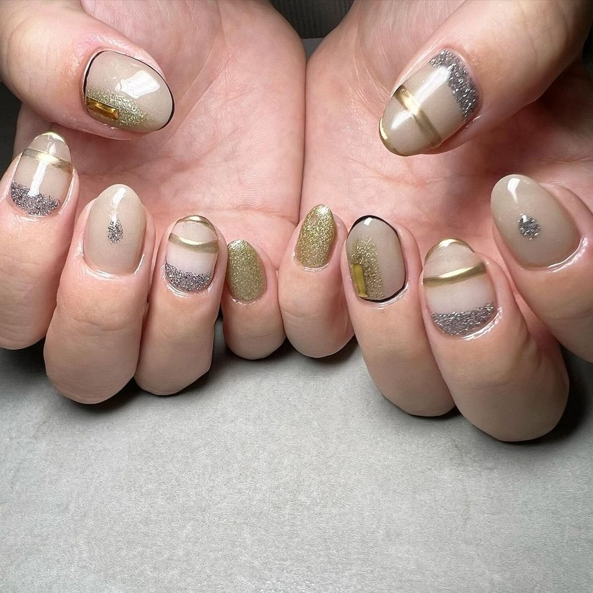 This image showcases stylish beige and gold glitter nails with various artistic designs, beautifully arranged on a clean surface.