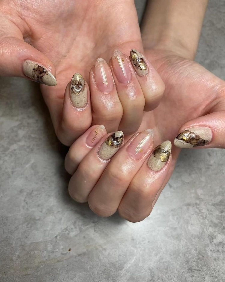 This image features stunning beige and gold nail art with intricate designs, showcasing stylish manicured hands.