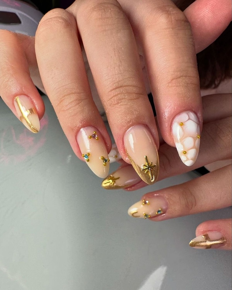 This image features beautiful beige and gold nails adorned with intricate designs and embellishments.