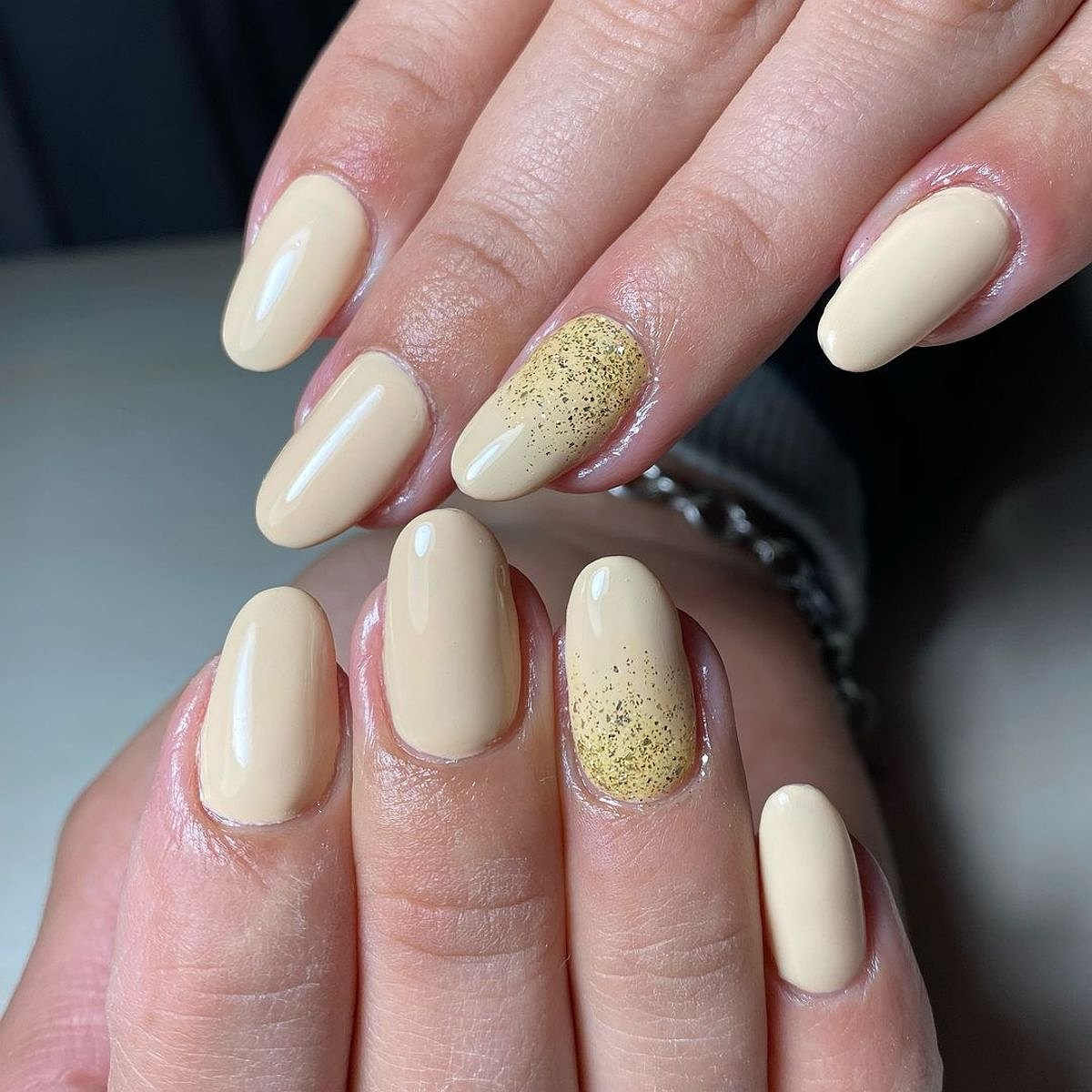 Stylish close-up of hands showcasing elegant beige and gold nail design, featuring multiple manicured fingers.