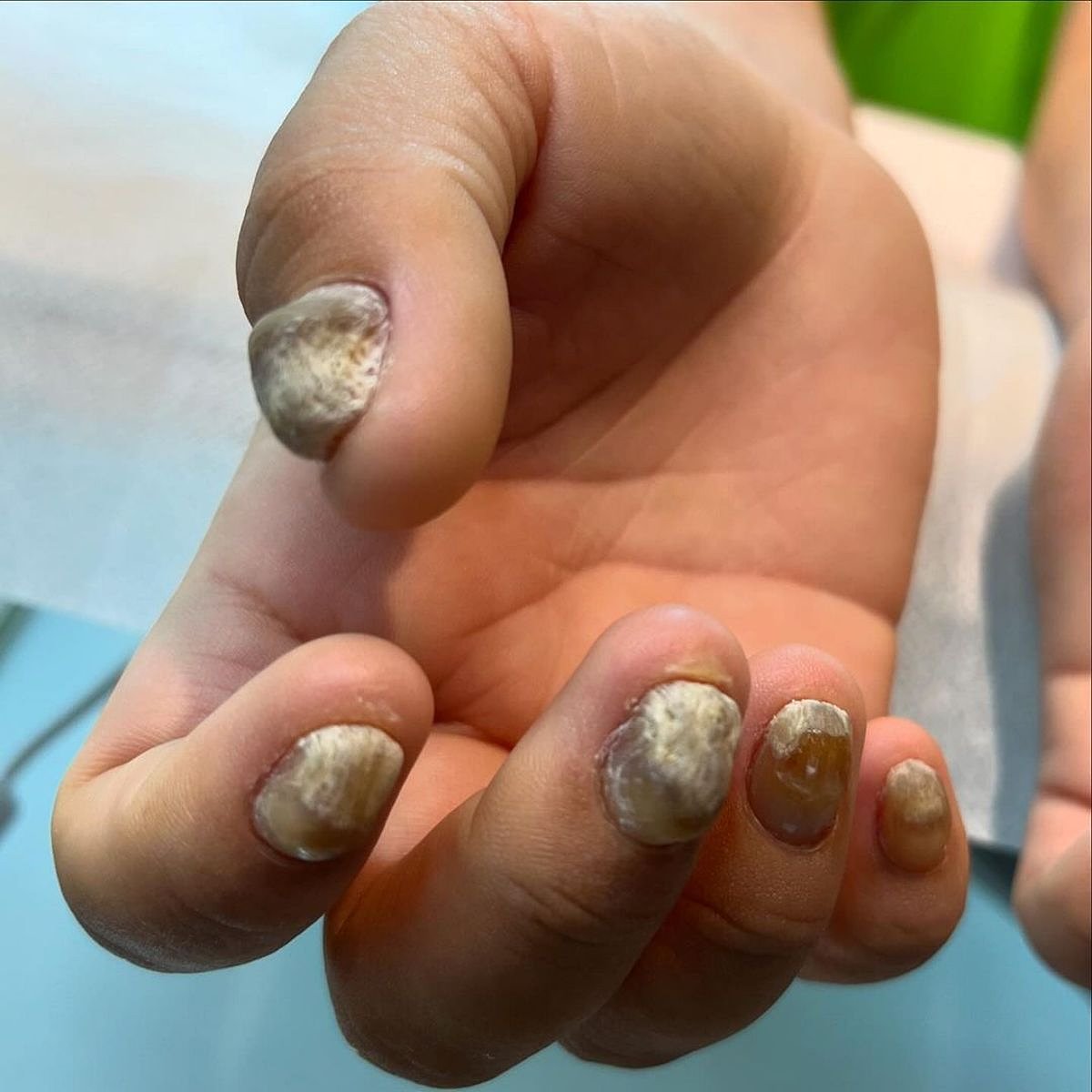 A close-up of stylish beige and golden nails with unique textures.