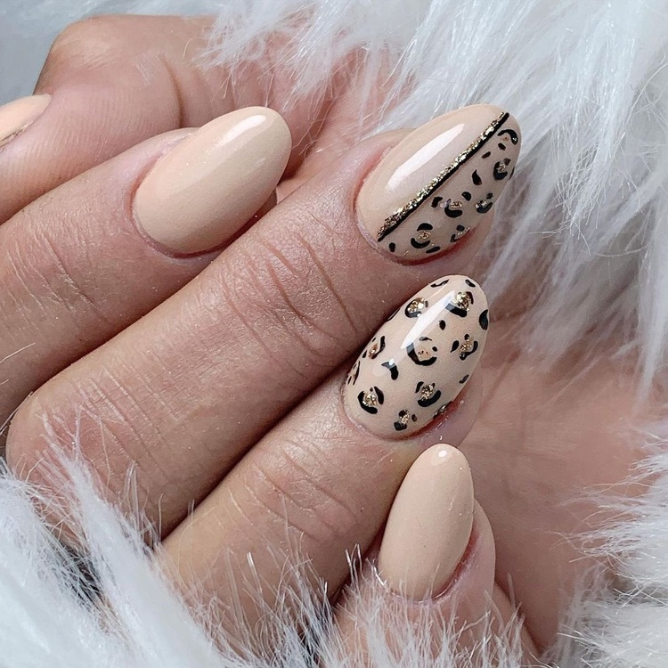 Stylish nails featuring a chic beige color with leopard print accents and gold striping on some fingers.