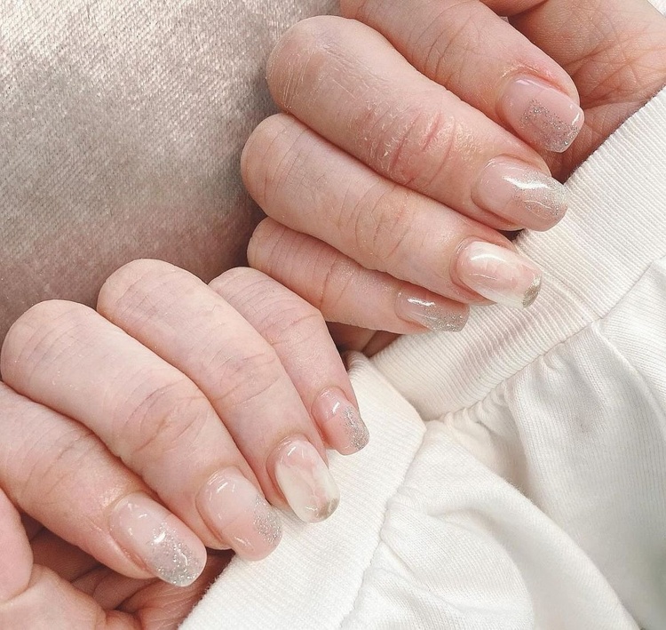 Beautiful long beige nails with a sparkly glossy finish, showcasing a delicate and stylish manicure.