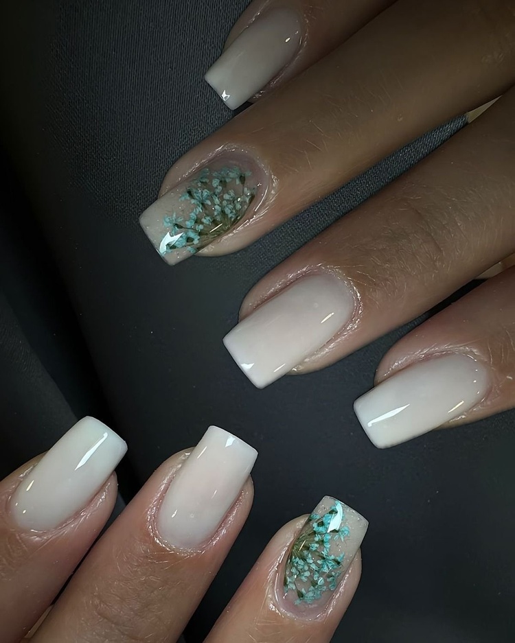 This image features beautiful beige square nails with aqua glitter designs among natural skin tones.