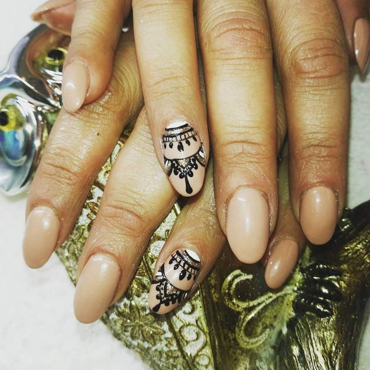 Beautiful beige nails featuring delicate black designs, showcasing elegant nail art.