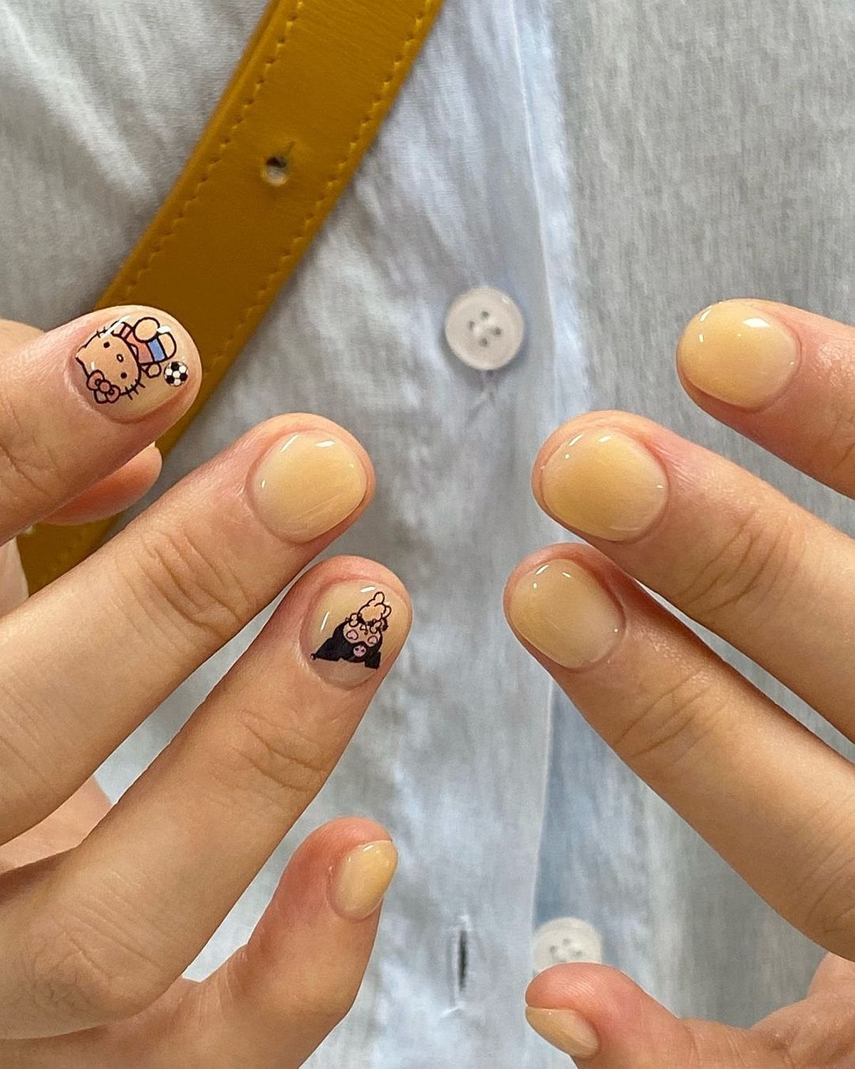 This image features beige nail designs with cute art on a person's fingers, showcasing a modern and playful style.