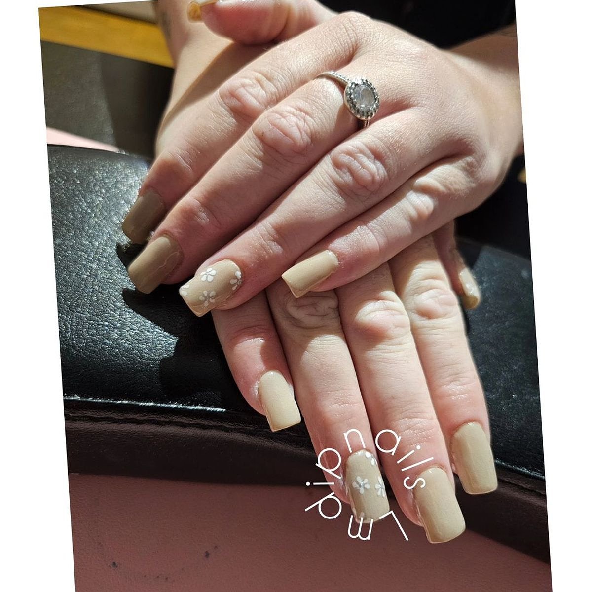 A close-up view of beautifully manicured beige nails featuring intricate nail art, set against a soft background.