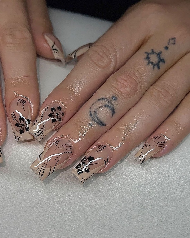 Beautifully designed beige nails featuring floral art and glossy details, with fingers highlighted.