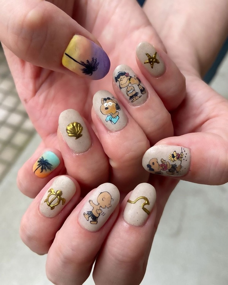 Beige nails adorned with palm trees, gold stars, and cartoon designs, showcasing creativity and fun.