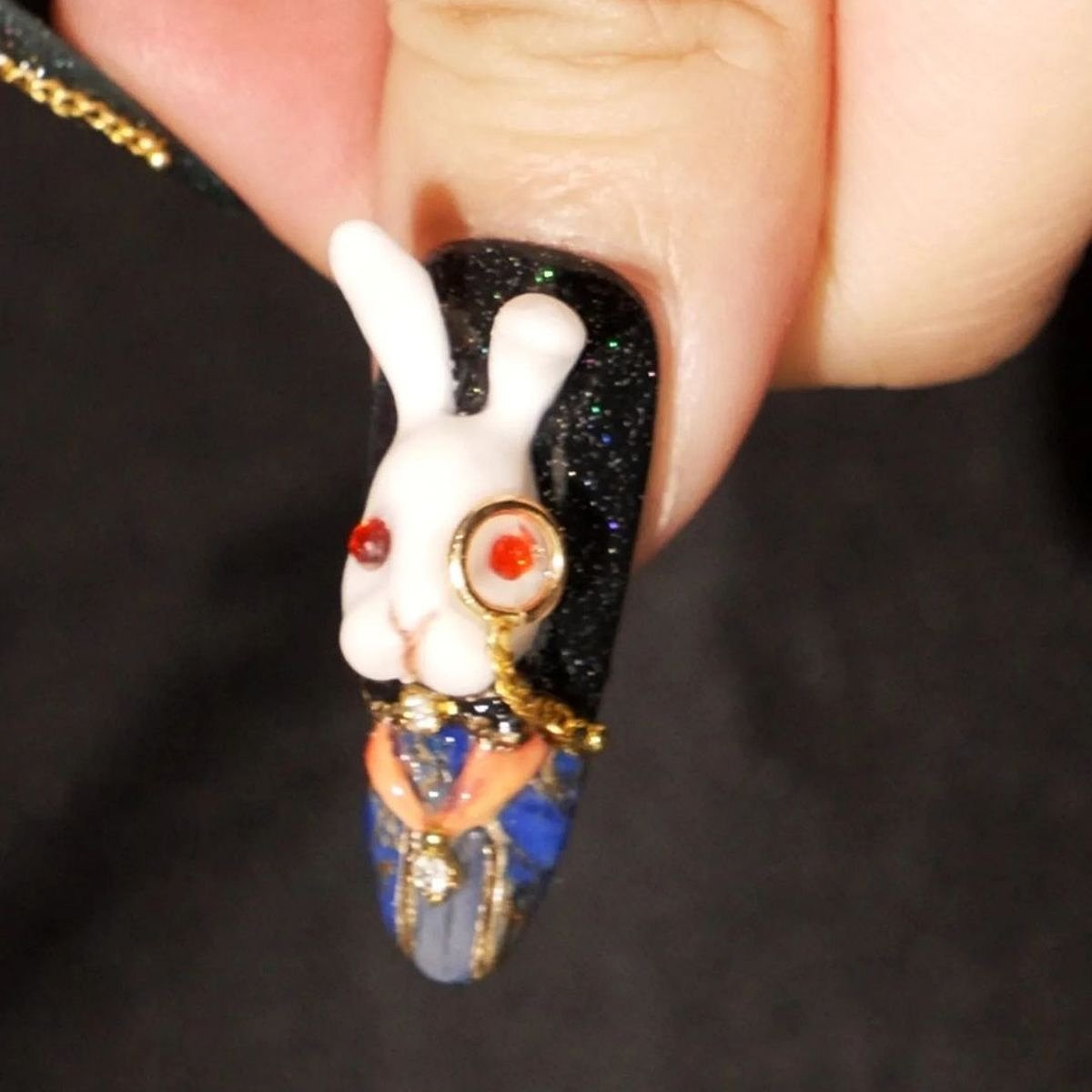 A detailed nail design featuring a black bunny figure with colorful accents against a neutral background.