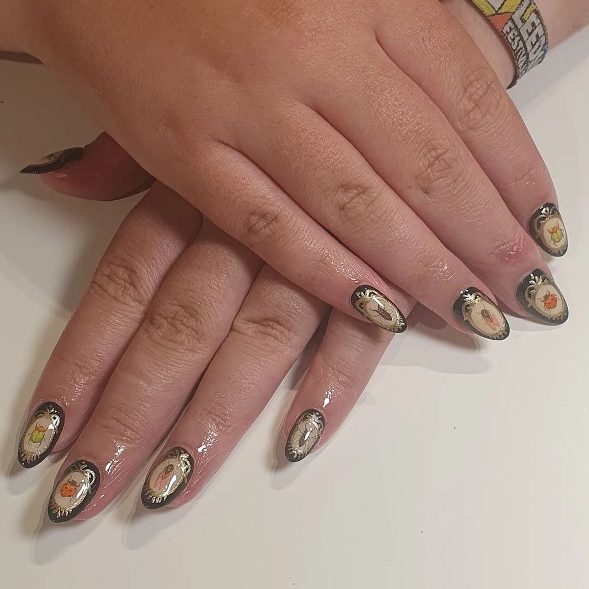 Stylish black nails with intricate green and orange art, showcasing unique designs, perfect for the fall season.