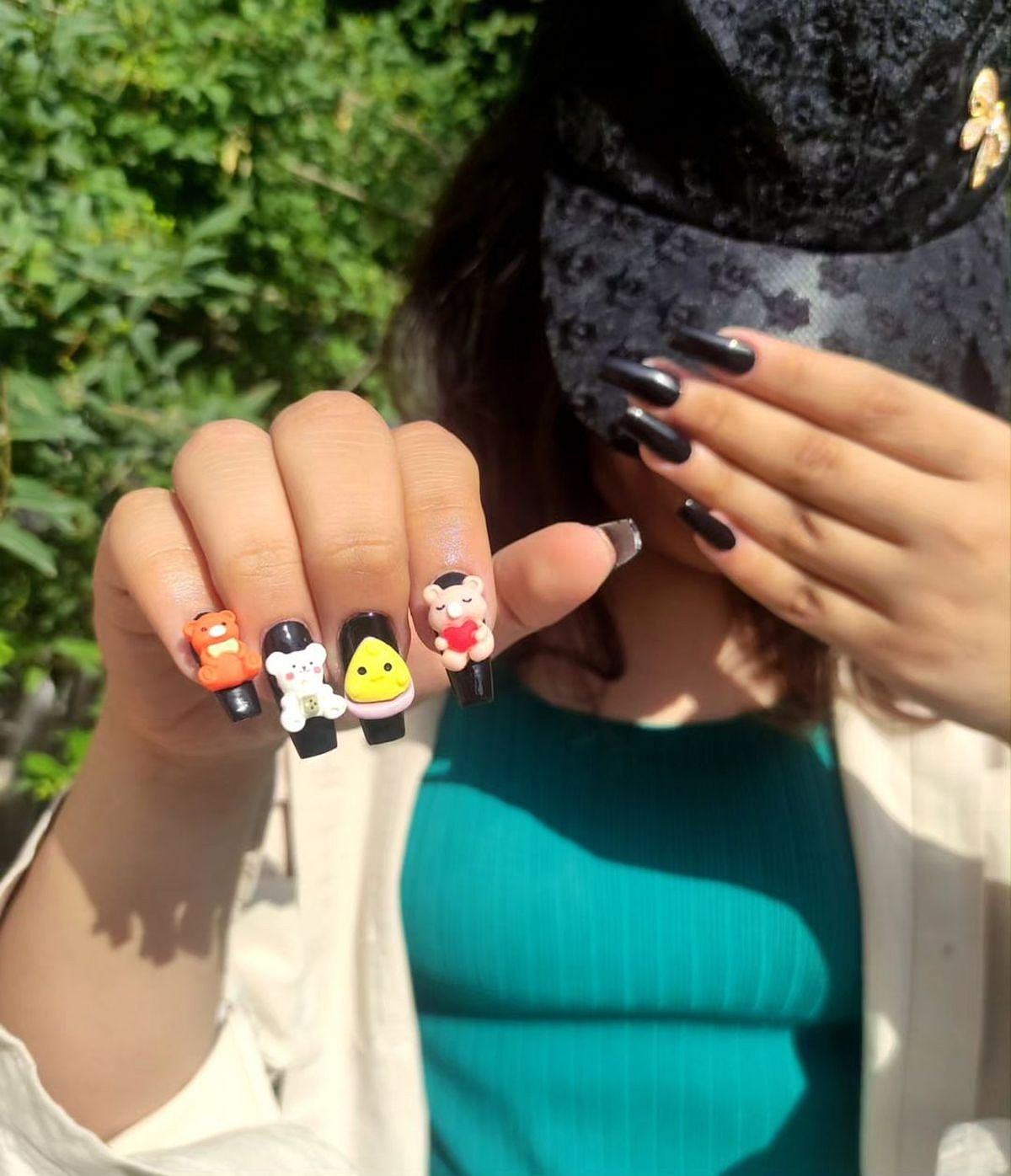 Stylish black long nails adorned with colorful character designs against a vibrant setting.