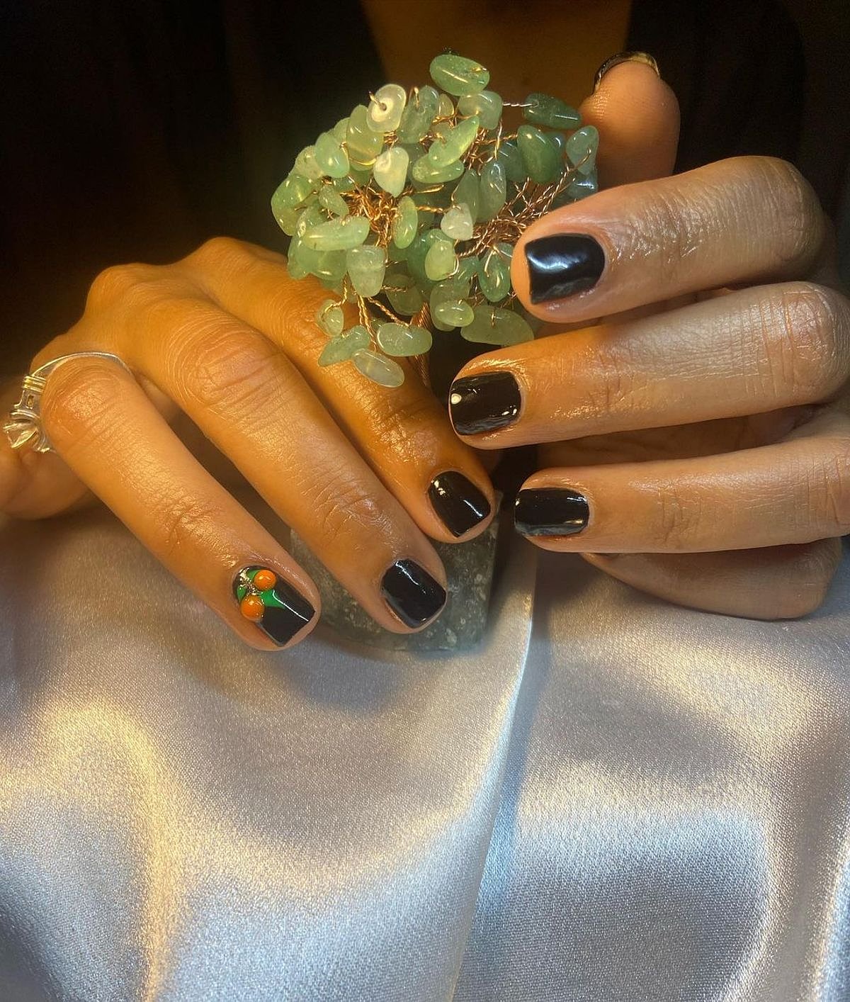 This image showcases elegant black nails with a colorful accent design, featuring a unique nail art against a softly lit background.