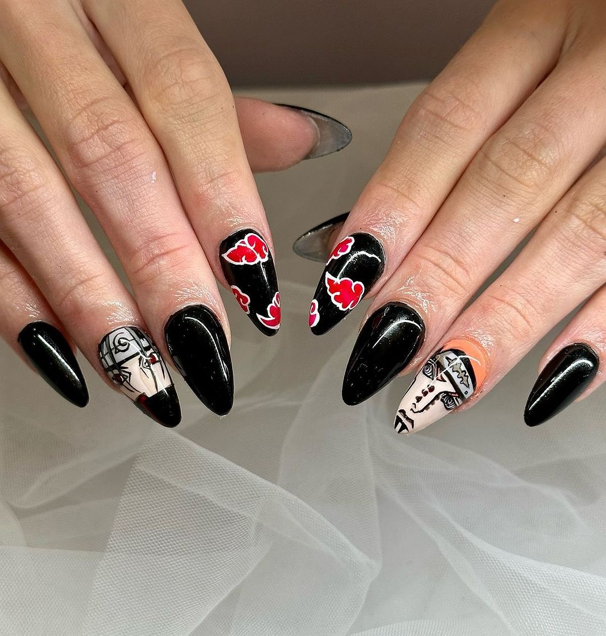 Close-up of stylish black nails featuring intricate designs and vibrant colors, set against a neutral background.