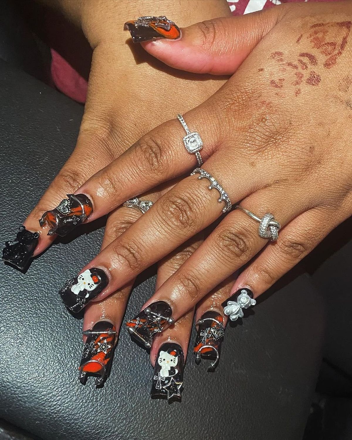 Stylish black and orange nails with gem accents and unique designs, showcasing creativity and elegance.