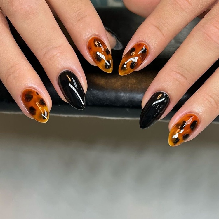 A set of stunning nails featuring black, orange, and gold colors with artistic designs.