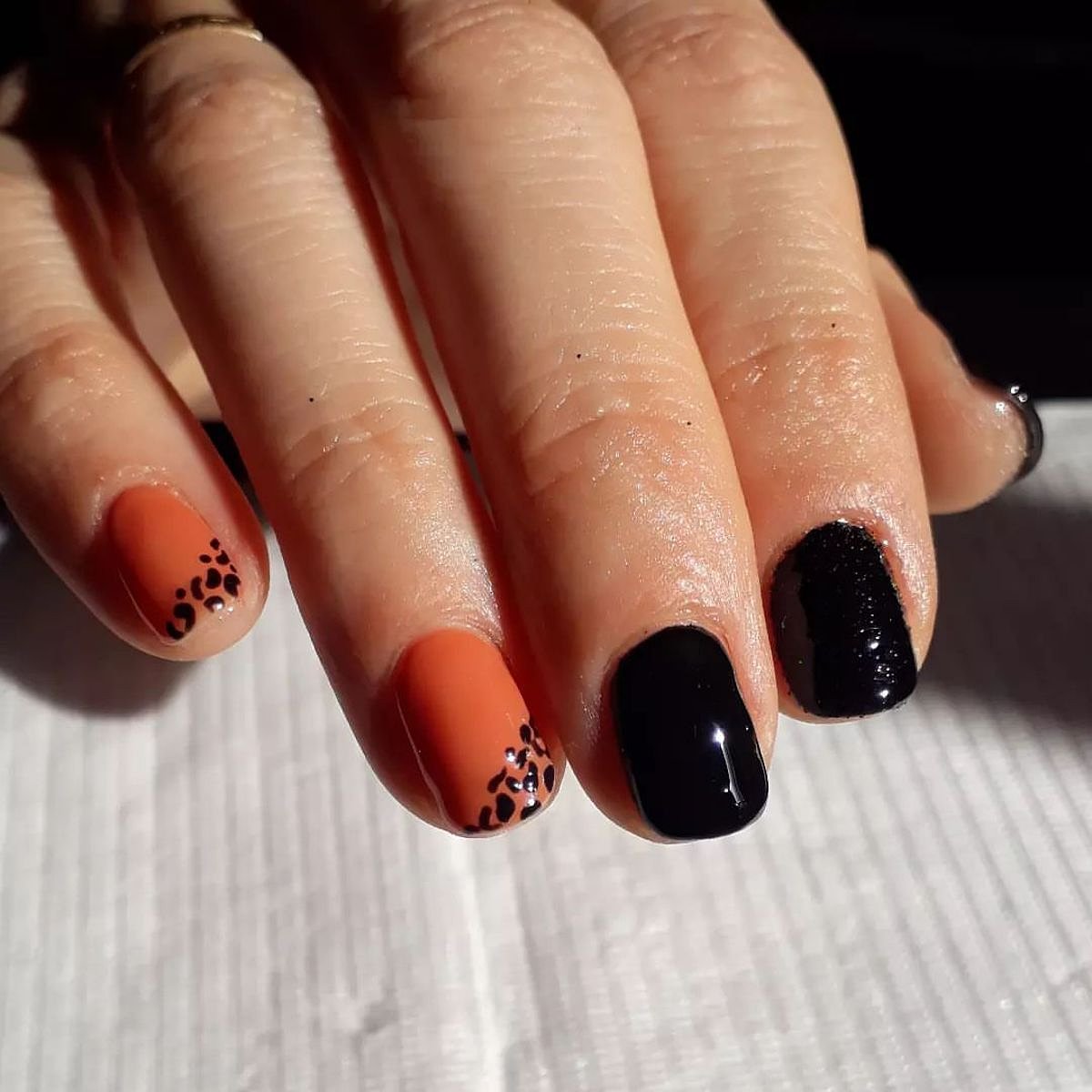 Perfectly manicured black and orange nails with intricate art.