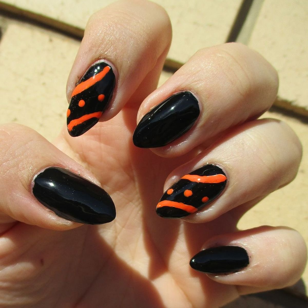 This image showcases beautiful black nails with striking orange nail art details.