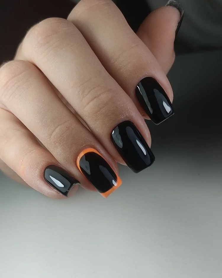 Elegant black and orange nails showcased on a hand with a polished finish.