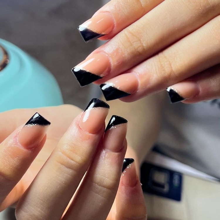 Close-up of beautifully manicured nails featuring a black and orange color scheme with stylish sharp tips.