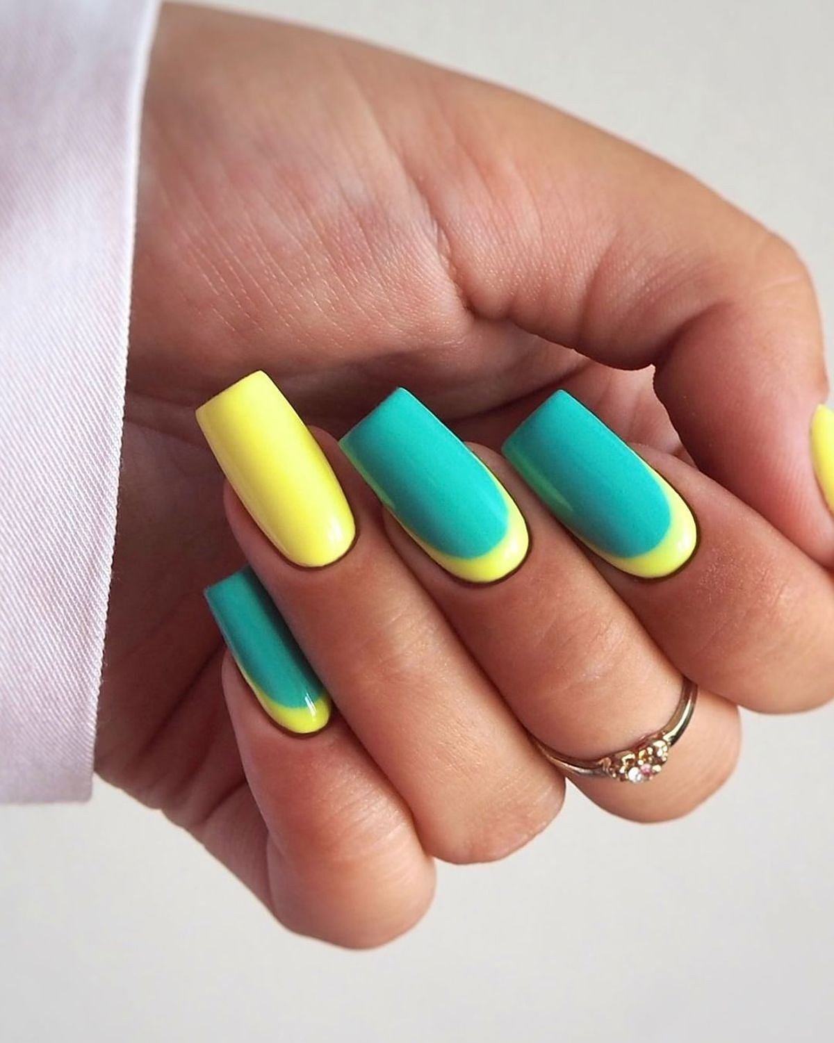 Bright yellow and teal nails create a refreshing and stylish look. A hand with vibrant yellow and teal nails showcasing a stylish manicure.