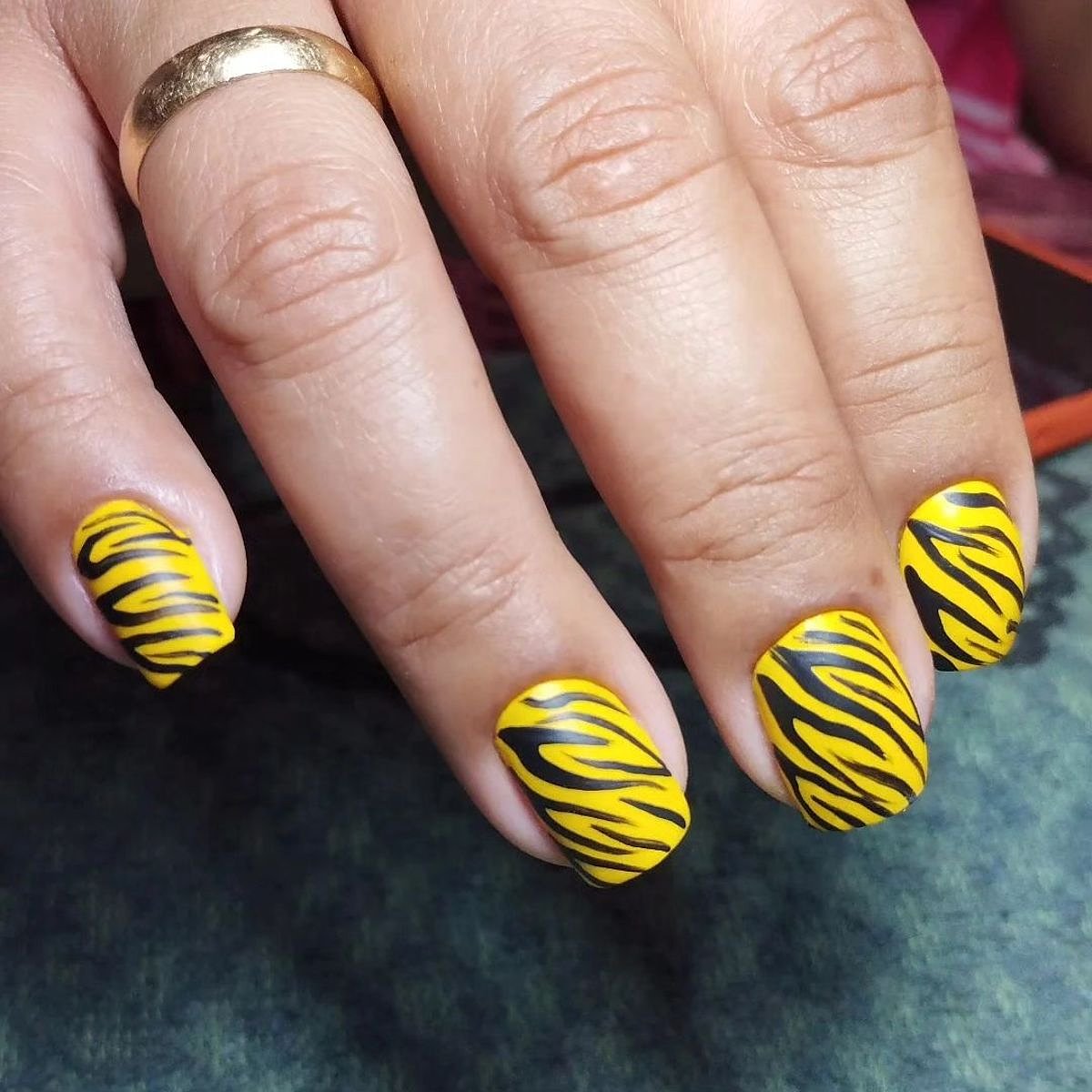 Close-up view of vibrant yellow nails with bold zebra stripes, showcasing a stylish manicure.