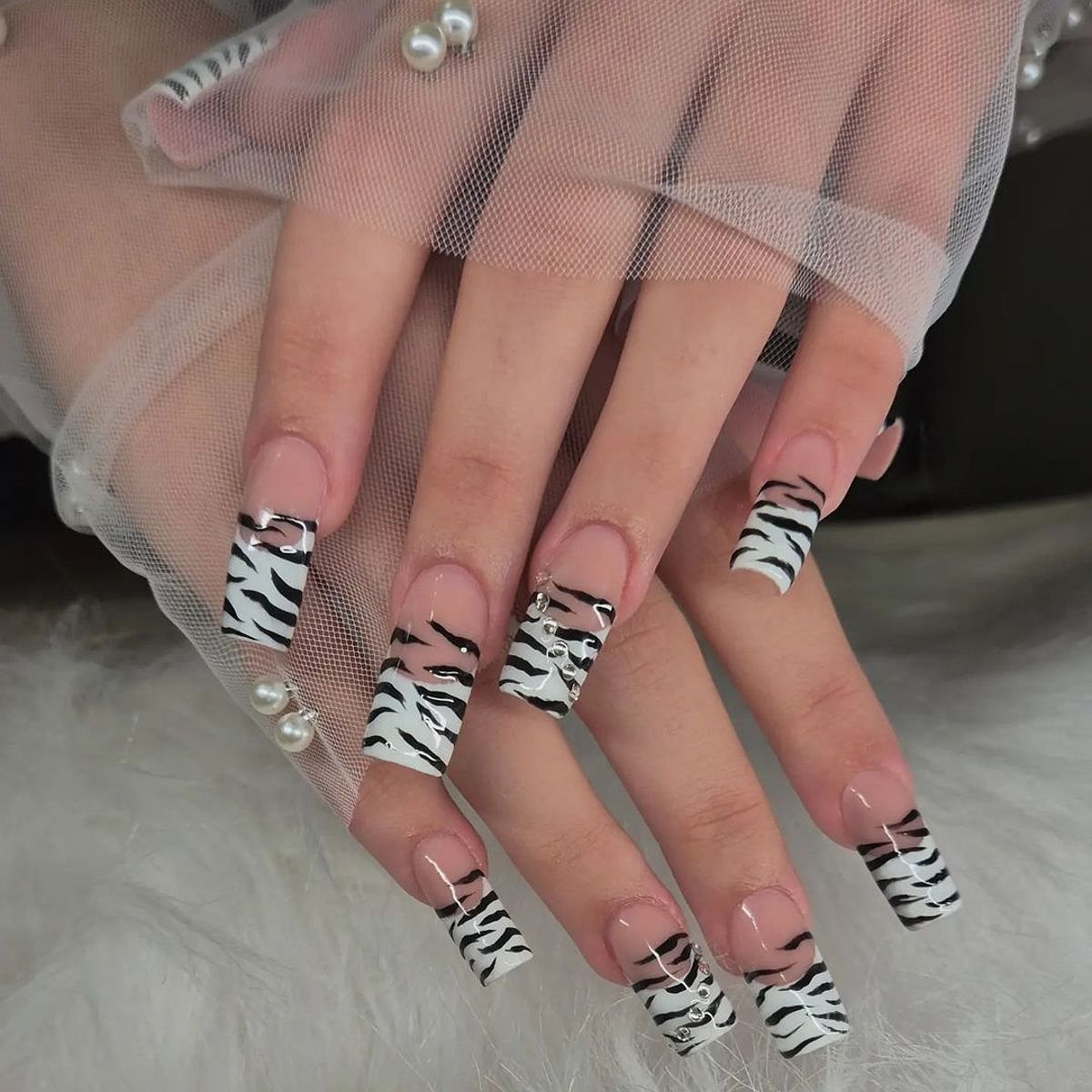 Elegant black and white zebra print nails adorned with delicate details.