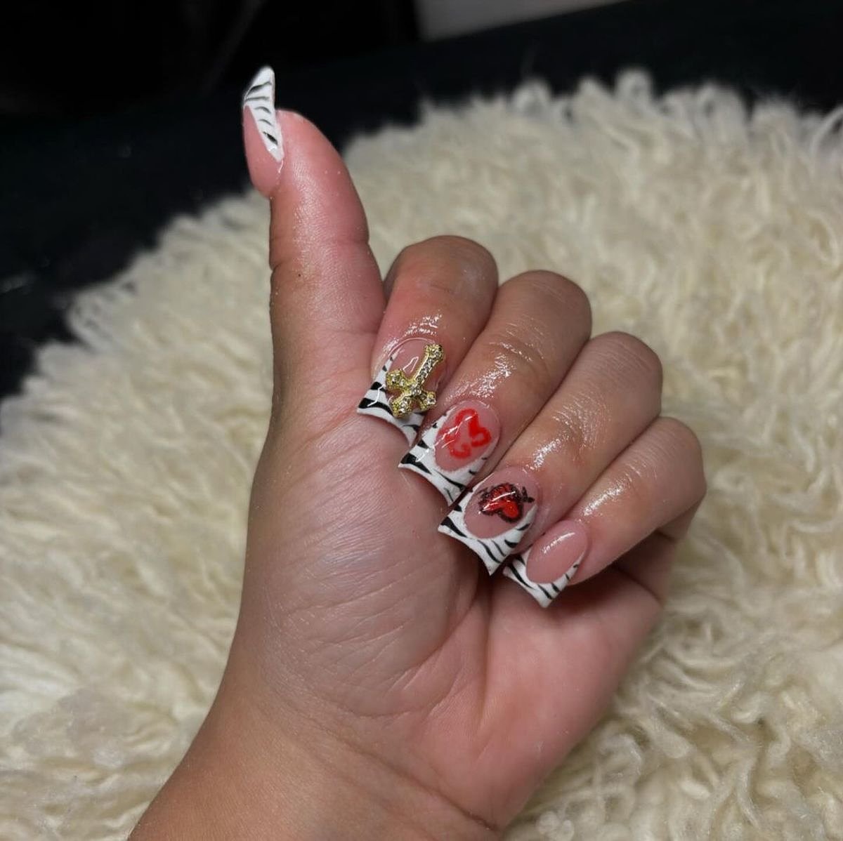 This photo features vibrant zebra print nails adorned with red and gold details, showcasing a chic manicure.